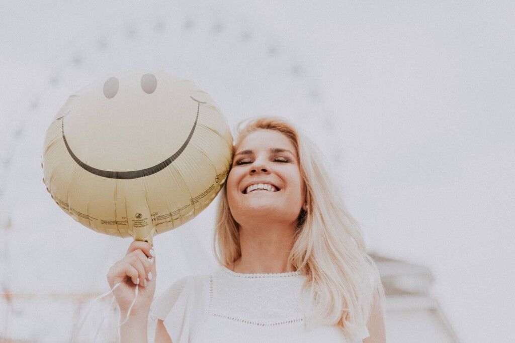 Motivoiva kuva naisesta jolla smile-ilmapallo ja leveä hymy