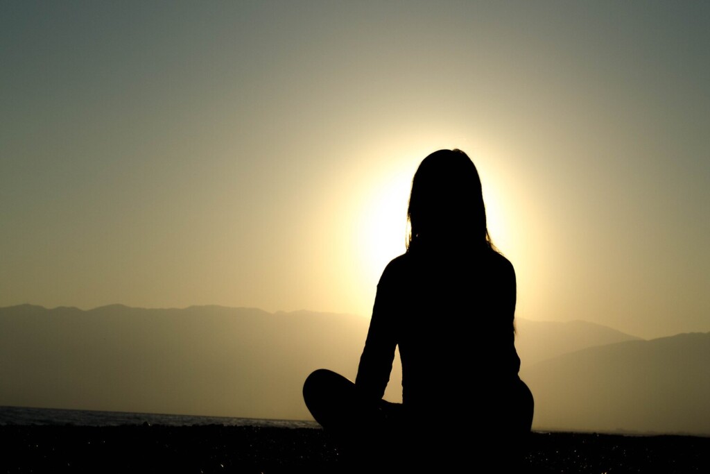 nainen meditoi auringonlaskun aikaan