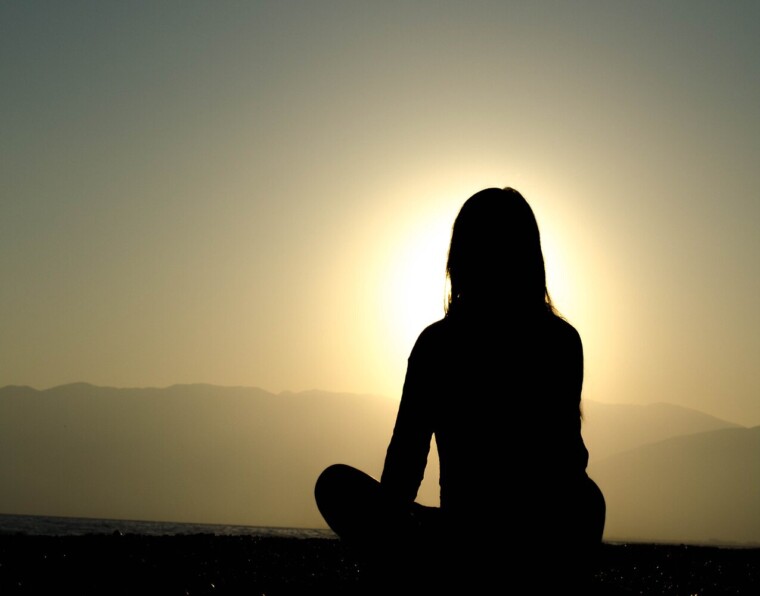 nainen meditoi auringonlaskun aikaan